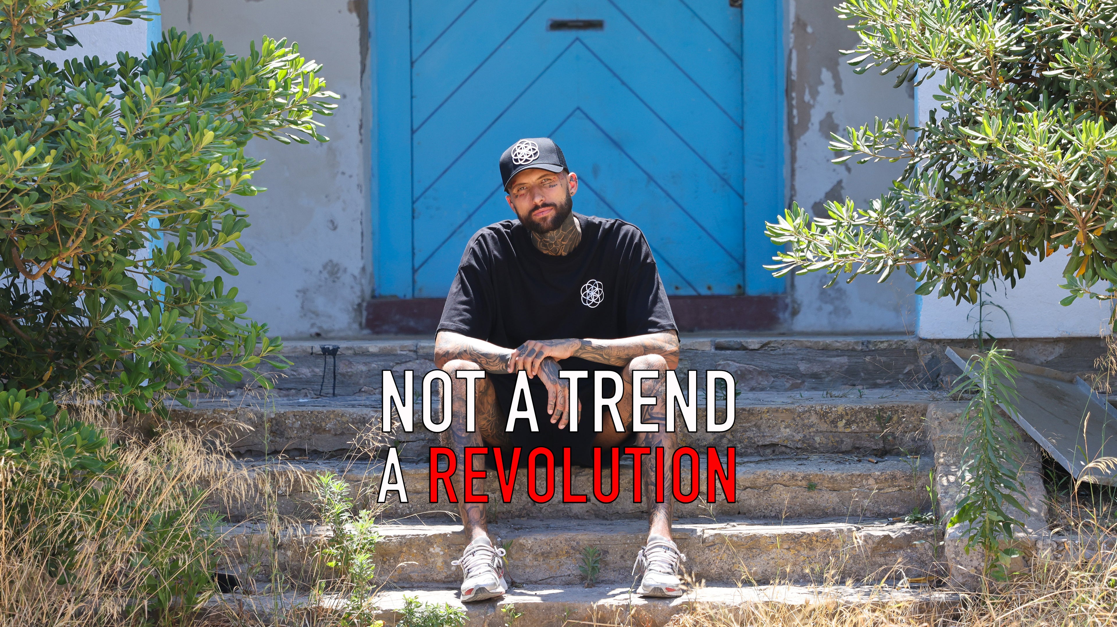 tattooed man sitting on steps wearing ScarTissue clothing, with the Seed Of Life logo